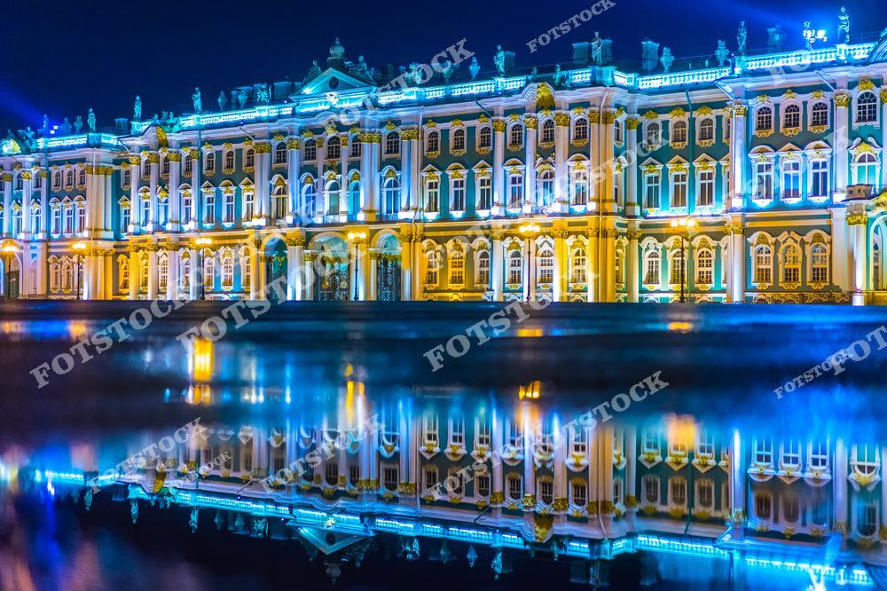 На фотографии изображен Зимний дворец в Санкт-Петербурге ночью. Здание, являющееся частью Эрмитажа, освещено яркой архитектурной подсветкой, подчеркивающей его величие и изящество. На переднем плане видно отражение дворца в воде, создающее эффект зеркального дубляжа. Это одно из самых знаменитых зданий города, символ его исторического и культурного наследия. Снимок прекрасно передает атмосферу ночного Петербурга.